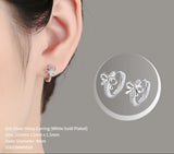 Silver hoop earrings with bow detail worn by a person, on a gray background.