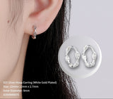 Silver hoop earring worn on an ear with a close-up inset showing the earring design.